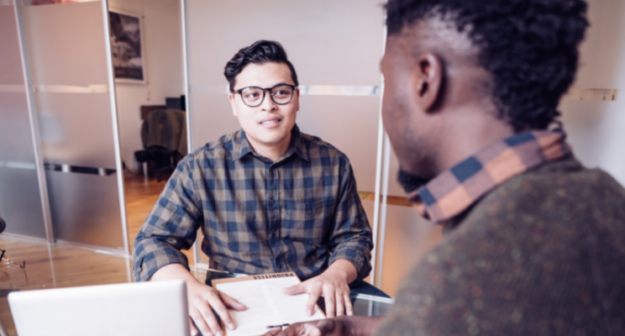 EmployeeCheckin Article Header Male leader and employee having a one-on-one conversation in an office