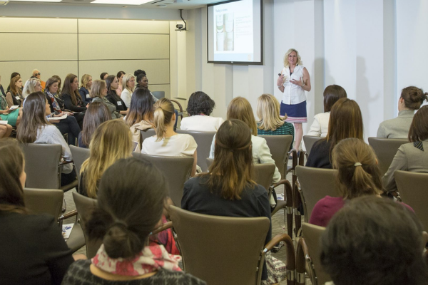Shani presenting a slideshow to a large group of people in a conference room