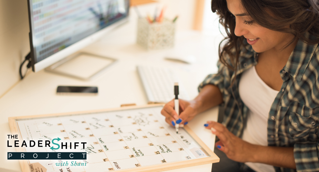 Blog-Burntoutatwork A woman writing in her white board calendar with a pen in her hand..