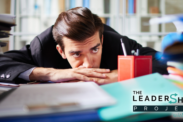 Exhausted office worker lying on desk surrounded with papers